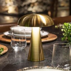 a table topped with plates and glasses next to a gold colored lamp on top of a counter