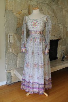 A stunning and rare dress with a mandala print A beautiful 60s maxi dress with a cotton lining and sheer overlay The fabric is a gauze type sheer The dress has an empire line and scoop open back Long sleeves with cuffs, these are not lined but are see through The colors are pink, green, and a dark blue Fits like a small to x small Label: House of Arts Made in India The mandala has great significance in buddhism signifying creation and the cosmos in a circle art form Measurements: 18 inches armpi Bohemian Maxi Dress With Empire Waist For Garden Party, Fitted Vintage Maxi Dress With Boho Print, Bohemian Empire Waist Maxi Dress, Bohemian Empire Waist Fitted Maxi Dress, Bohemian Fitted Maxi Dress With Empire Waist, Bohemian Fitted Full-length Maxi Dress, Fitted Bohemian Full Length Maxi Dress, Vintage Maxi Dress With Boho Print, Vintage Maxi Length Dress With Boho Print