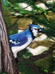 a blue bird sitting on top of a tree next to a green and white blanket