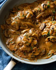 a pan filled with meat and mushrooms covered in gravy on top of a blue towel