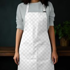 a woman wearing an apron standing in front of a table with a potted plant