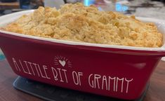 a red casserole dish filled with food sitting on top of a wooden table