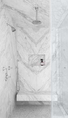 an instagram photo of a bathroom with white marble walls and floor, along with a shower head