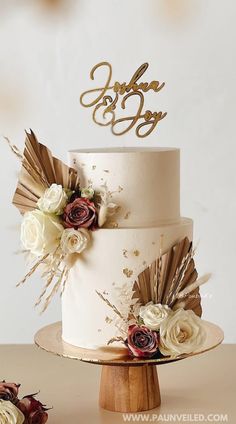 there is a wedding cake with flowers on the top and two initials on the side