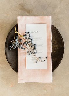 a plate with a napkin and some flowers on it next to a piece of paper