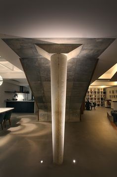 the interior of an office building with concrete columns and tables in front of bookshelves