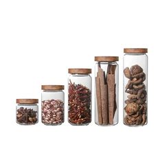 four glass jars filled with different types of spices and cinnamons on a white background