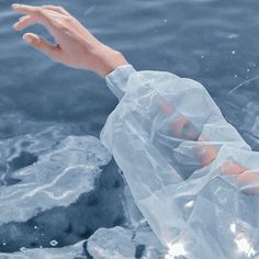 a hand reaching out from the water to grab something in it's plastic bag