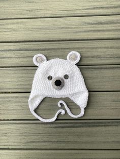 a crocheted white hat with a bear face on the front and ear flaps