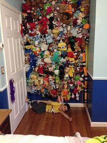 a child is laying on the floor in front of a wall full of stuffed animals