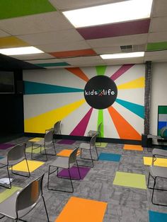 an office with colorful carpet and chairs in front of a large sign that says kid's life