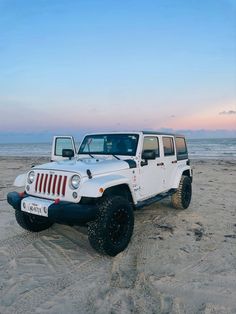 two white jeeps are parked on the beach