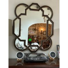 a large mirror sitting on top of a wooden table next to a bluetooth speaker