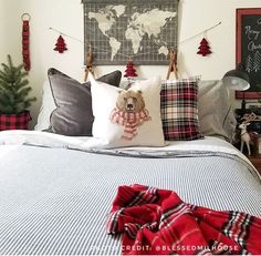 a bed with plaid blankets and pillows on it, next to a christmas tree in the corner