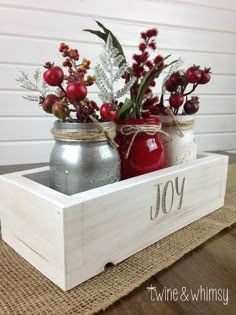 two mason jars with flowers in them are sitting on a table next to a wooden crate