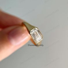 a close up of a person's hand holding a ring with a diamond in it