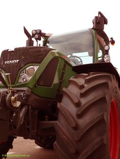 a large green tractor parked on top of a dirt field