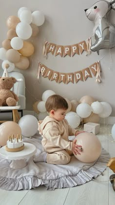 a baby sitting on the floor in front of some balloons and other birthday decorations,