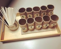 a wooden tray with cups and straws on it next to a set of numbers