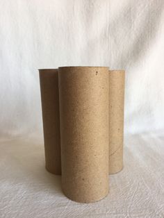 three brown paper cups sitting next to each other on a white tablecloth covered surface