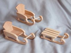 two wooden toy sleighs sitting next to each other on a white sheet