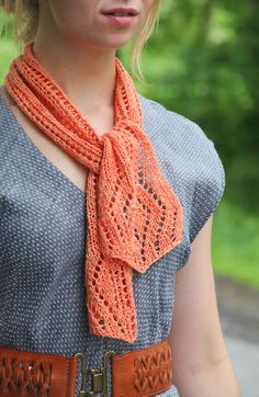 a woman wearing an orange knitted scarf with a brown leather belt around her neck