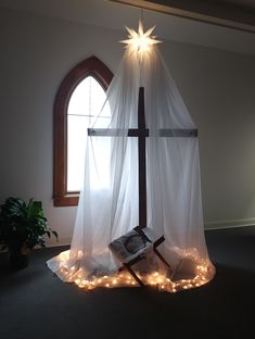 a cross with lights around it in front of a window