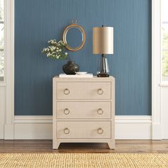 a white dresser with a mirror and vase on it in a blue walled living room