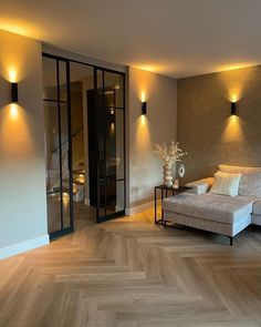 a living room with wood flooring and two lamps on the side of the wall