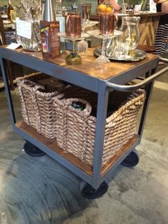 a table with baskets and bottles on it in a room filled with other items such as wine glasses