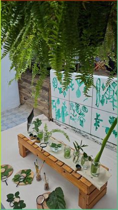 an outdoor table with plants and plates on it