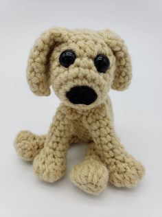 a crocheted dog sitting on the floor with its eyes wide open and black nose