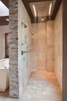 a walk in shower sitting next to a stone wall and tiled floored bathroom area