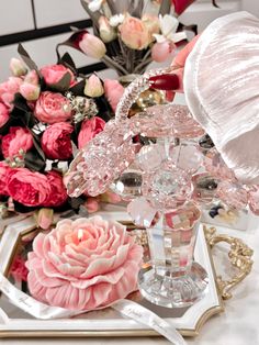 pink flowers are sitting on top of a white tray with glass vases in the background