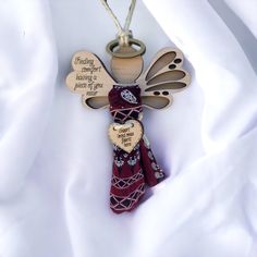 a wooden angel ornament with two hearts attached to it's sides, on a white cloth