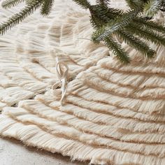 a close up of a tree branch on a white rug with fringes and beads