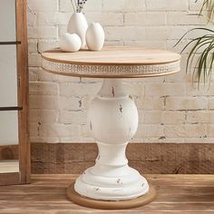 three white vases sitting on top of a wooden table next to a brick wall