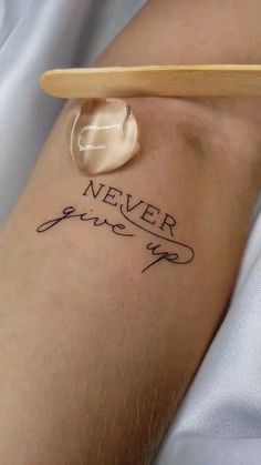 a person with a tattoo that says never give up on their arm and the word is written in cursive writing