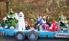 a parade float with people dressed in costumes on it's flatbed, decorated for the holiday season