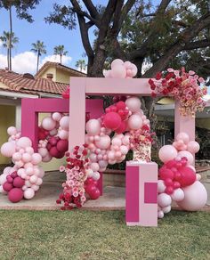 a pink and white balloon arch in front of a house