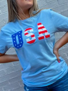 Stay festive and show off your star-spangled style with this USA Chenille Light Blue T-Shirt! It's the perfect top for any Fourth of July occasion. Stars and stripes in red, white, and blue with the chenille fabric make it truly patriotic and SUPER stylish! Boom! 💥 Unisex sizing and fit SPECIAL CARE - WASHING INSTRUCTIONS: Hand washing and air drying are always best for these items. Wash on delicate, cold, and inside out. Always air dry to prevent lint from sticking to the letters and for longe Patriotic Star Print Short Sleeve T-shirt, Patriotic Star Print Short Sleeve Tops, Casual Blue Tops With American Flag Print, Patriotic Short Sleeve Top With Star Print, Patriotic Short Sleeve T-shirt With Star Print, Americana Crew Neck Tops For Summer, Patriotic Blue Tops For Summer, Summer Americana Crew Neck Top, Blue Patriotic Tops For Summer