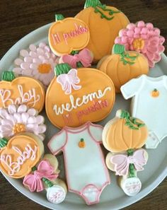 baby shower cookies decorated like pumpkins and flowers on a plate with the word welcome