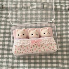 three little bears are sitting in a plastic container on a tablecloth with gingham cloth