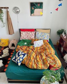 an unmade bed with many pillows and blankets on it in a room filled with stuffed animals