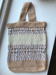 a crocheted bag sitting on top of a white table next to a bowl