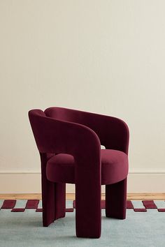 two purple chairs sitting on top of a blue rug in front of a white wall