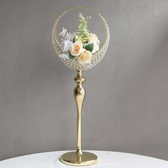 a gold vase with flowers in it sitting on a table