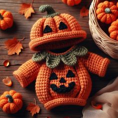 an orange crocheted pumpkin outfit sitting next to small pumpkins on a wooden table