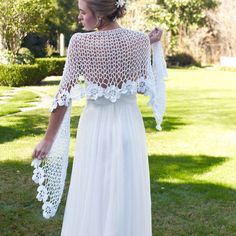 a woman in a white dress is standing on the grass with her back to the camera