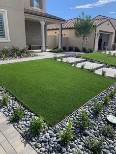 a lawn with rocks and grass in front of a house